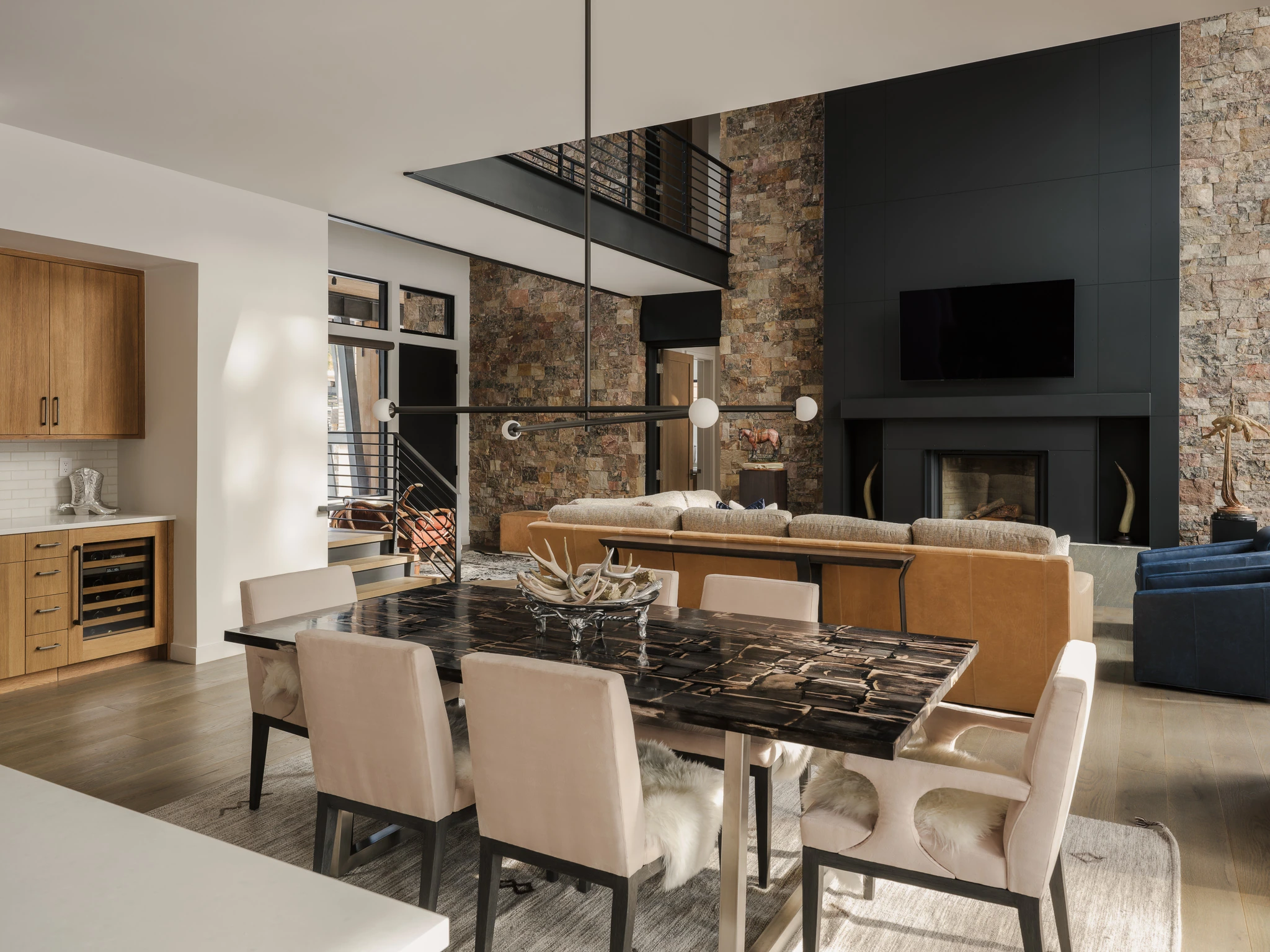 Great room and dining table beneath a stone fireplace wall — interior design photography Big Sky Montana, Speedwell Cabin
